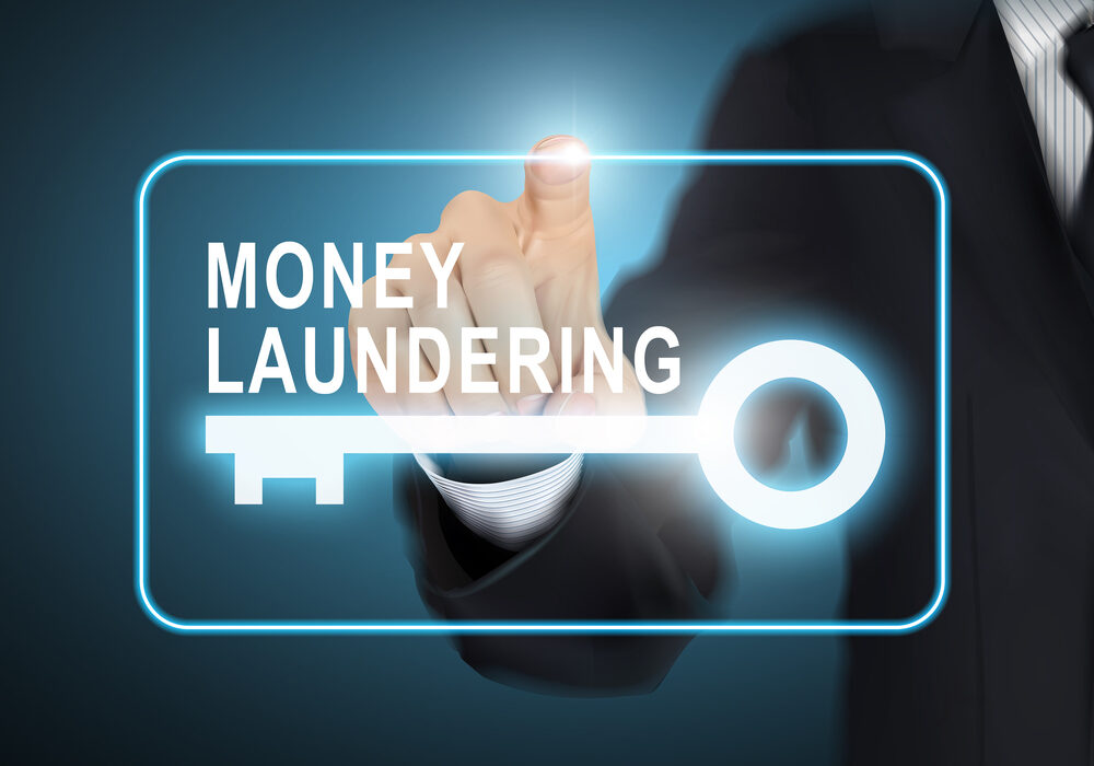 male hand pressing money laundering key button over blue abstract background