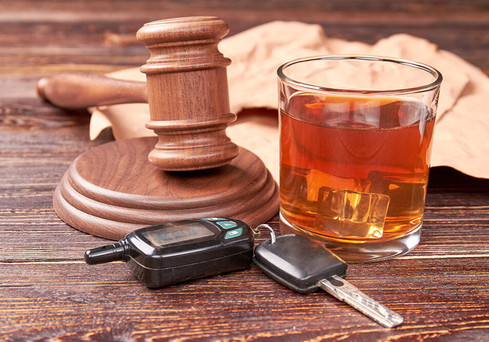Drunk driving concept. Driving keys, gavel, glass of whisky on wooden background. Drink and drive is hard crime.