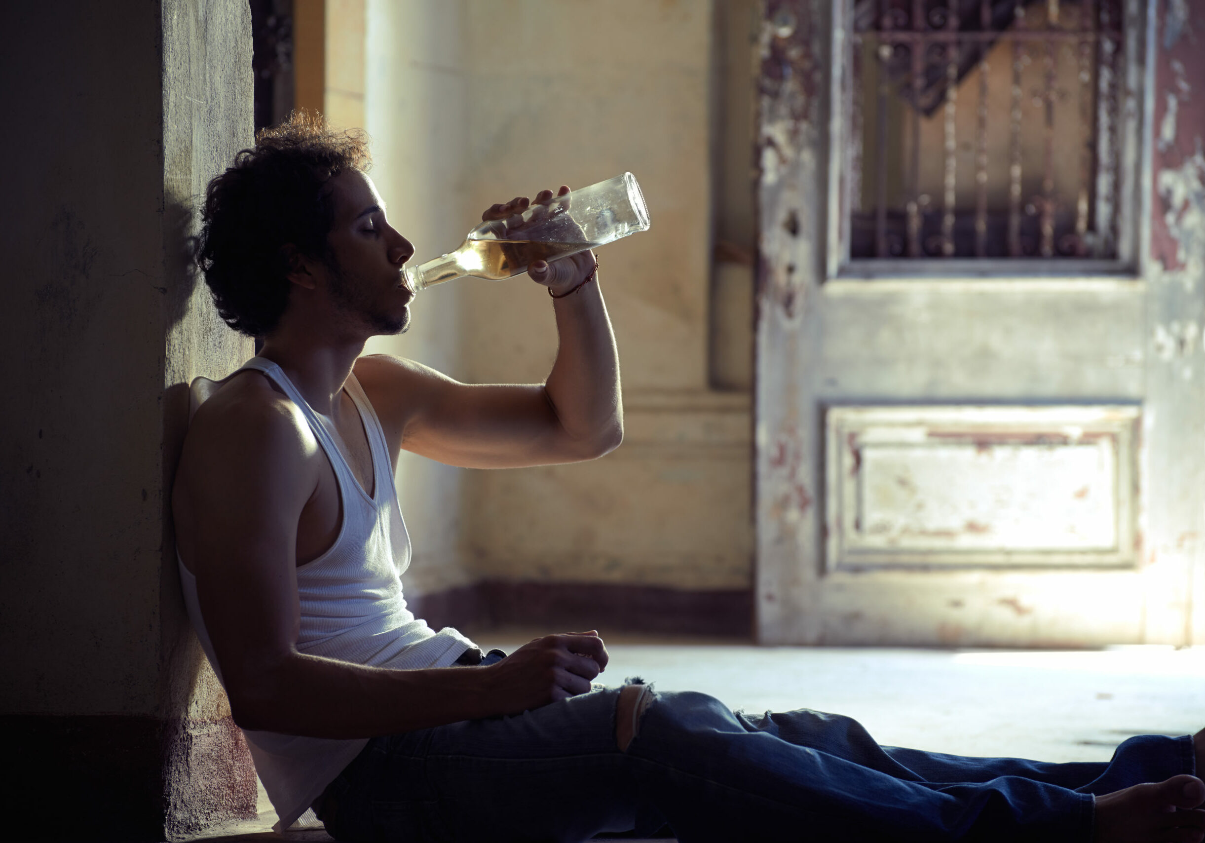 People, substance abuse and domestic violence. Portrait of young alcoholist drunk male drinking whisky at home