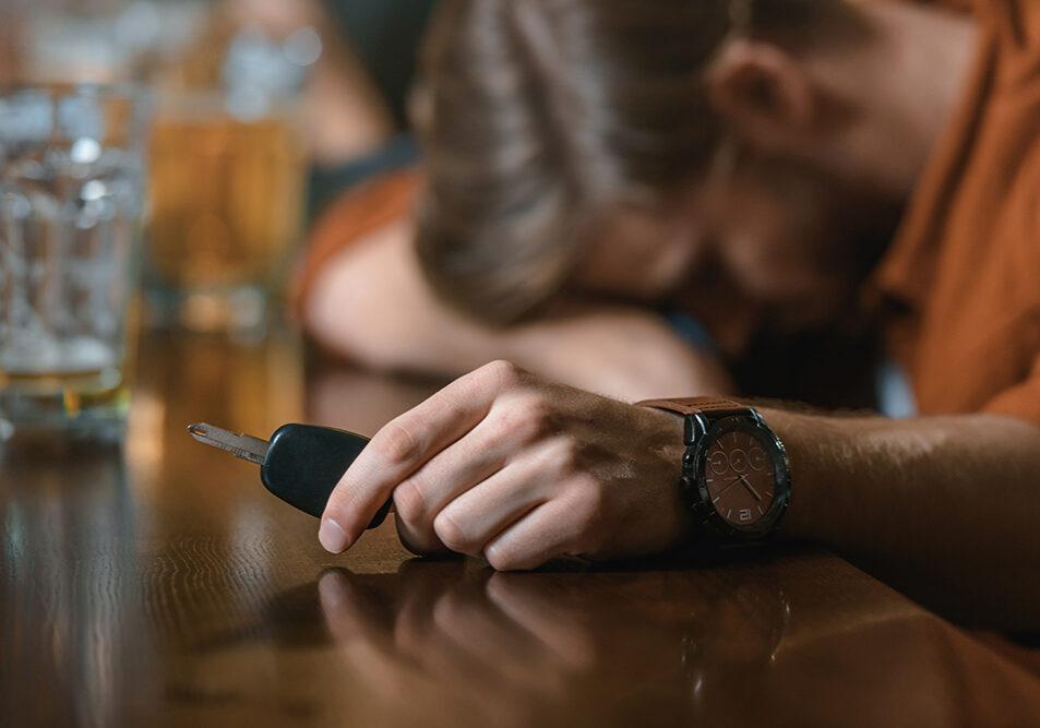 very drunk caucasian man with automobile keys at bar with friends
